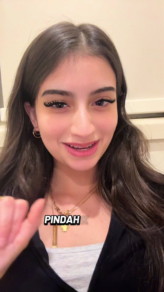 Video cover: Aisha smiling to camera in a dark top.